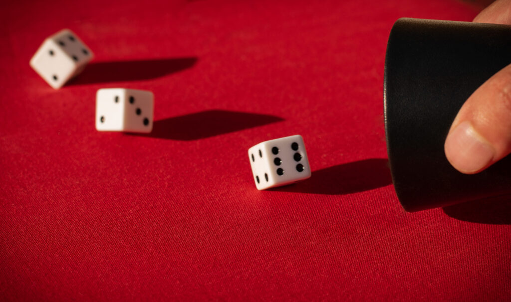 selective-focus-shot-dices-falling-out-dice-shaker-red-surface (1)